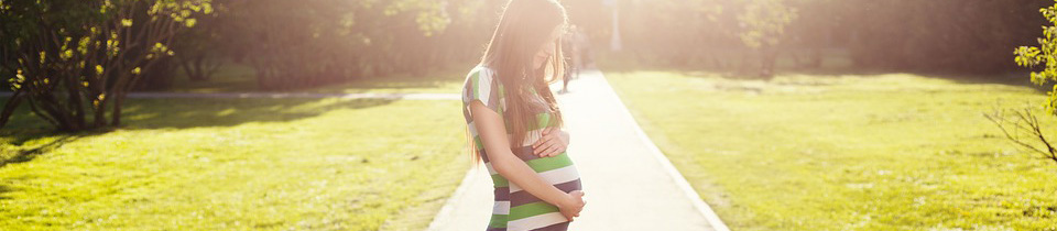 A pregnant woman looking down and holding her stomach