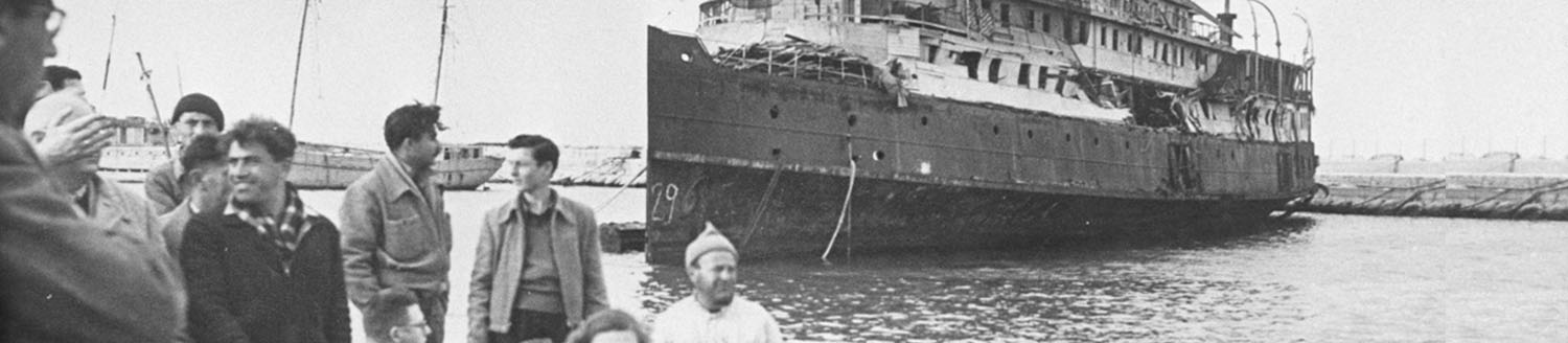 Immigrants standing at a dock in front of a ship