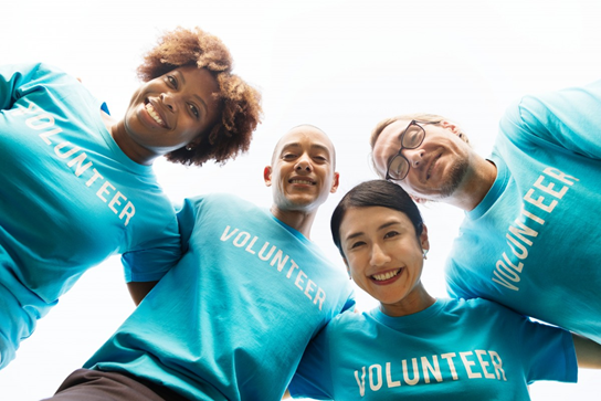 Group of volunteers in a huddle looking down into camera