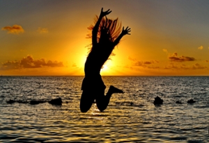 Lady gleefully jumping on the beach