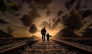 A father and a child walk on train tracks