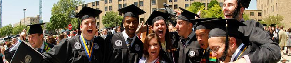 Photo of a group of friends smiling at graduation in caps and gowns