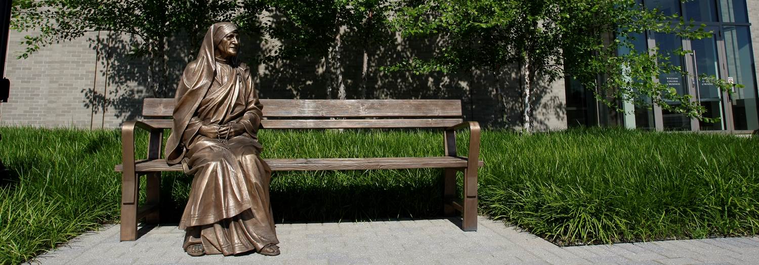 Photo of a gold statue of Mother Teresa sitting on a gold bench
