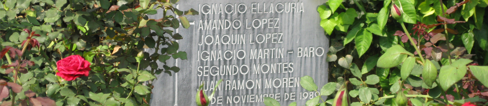 A photo of the UCA Martyrs of El Salvador written on a stone of some kind with flowers surrounding it