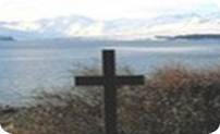 Picture of a wooden cross overlooking a lake.