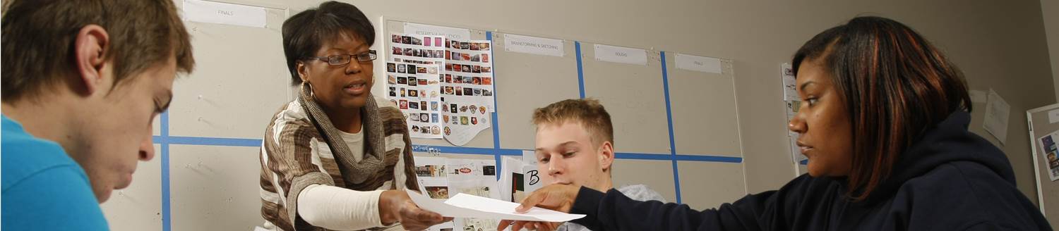 Photo of a professor handing out papers to students