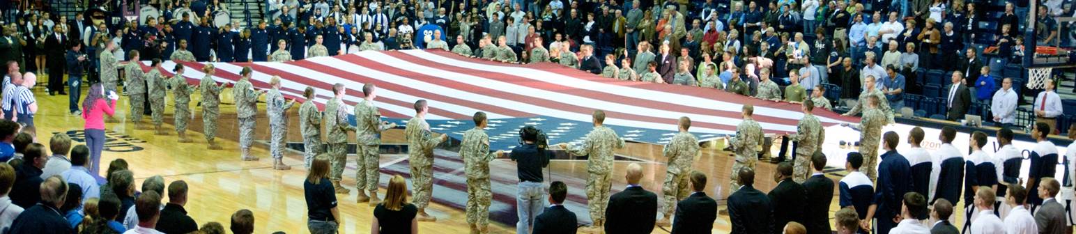 Photo of military members holding the American flag in the Cintas Center
