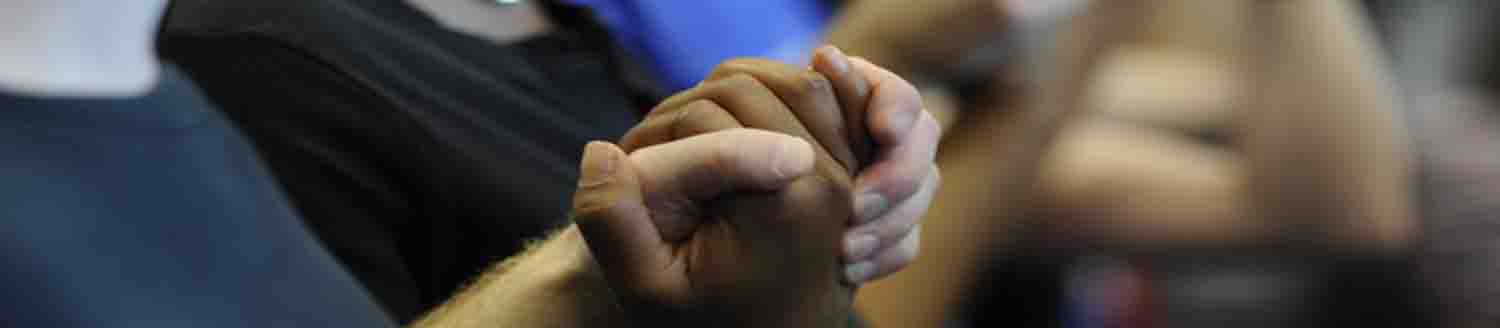 A photo of two people holding hands in prayer