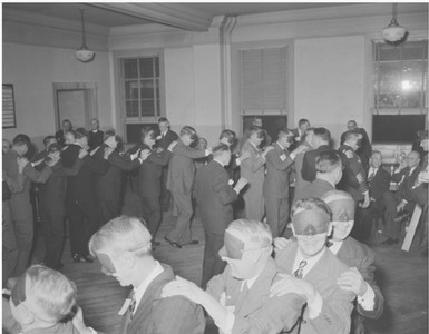 A group of men being led blindfolded in freshmen dads initiation, 1941