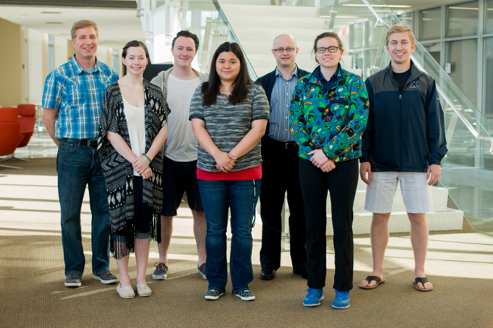 Group of six adults smiling together inside of the Conaton Learning Commons atrium