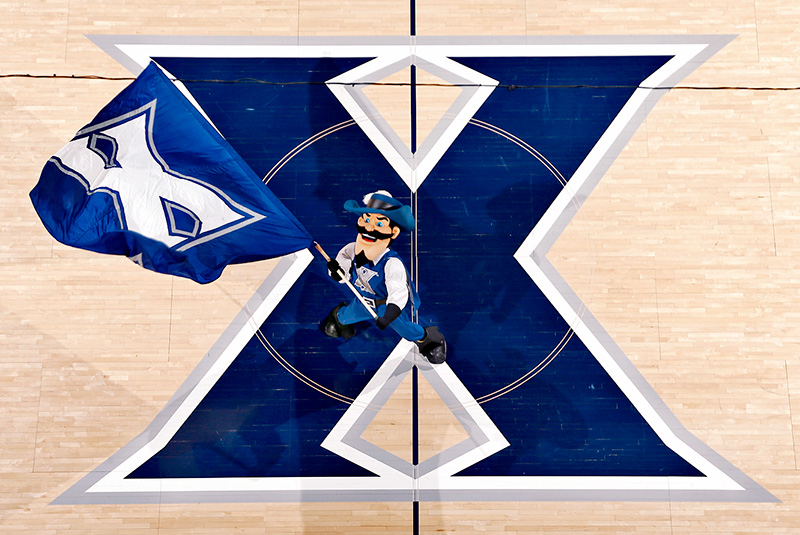 D'Artagnan, one of Xavier's mascots, runs across the Cintas court waving a flag with the Xavier logo on it