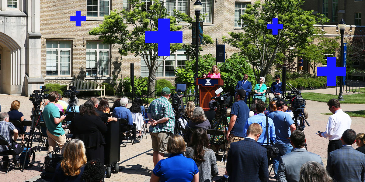 Journalists and Xavier leadership gathering outdoors during a press conference