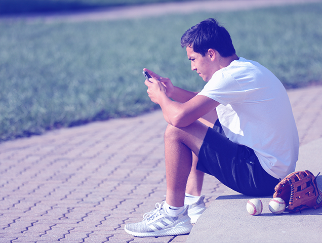 A student sits on campus and reads something on their cell phone