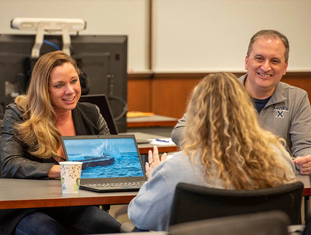 Executive MBA students gathered laughing and working on the capstone