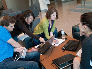 Four students working collaboratively on laptops