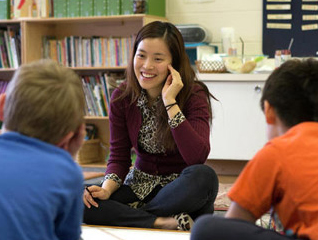 Educator sitting cross legged with two elementary-age students