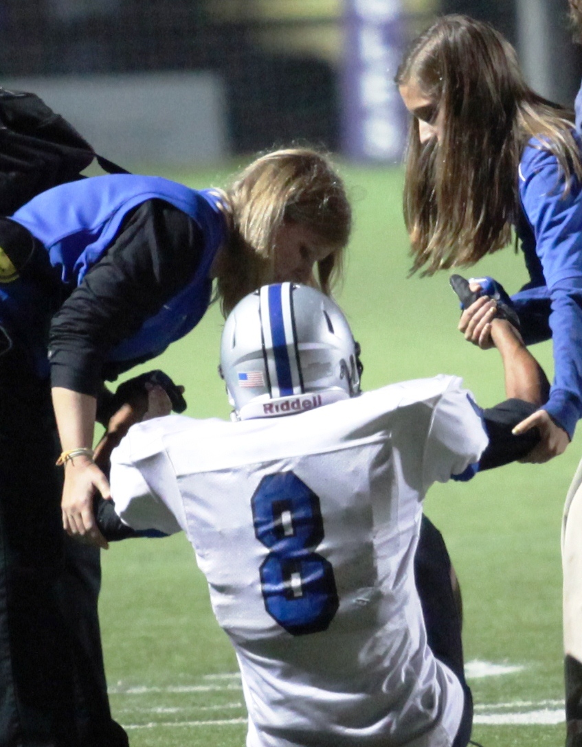 Two assistants helping an injured football player off the field photo