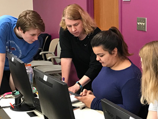 A professor showing a student in the mathematics major how to do something on a computer