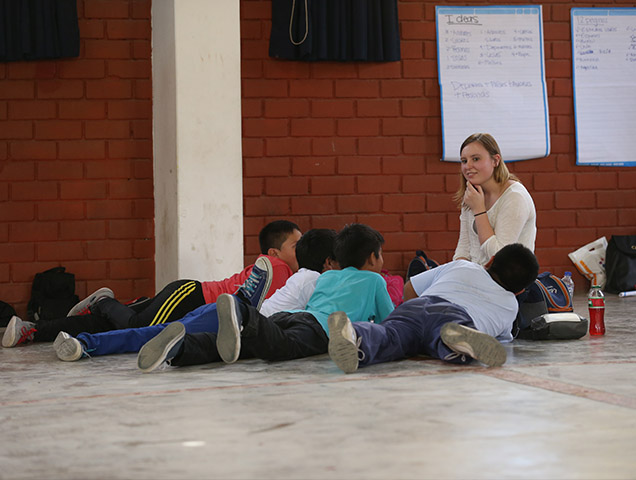 A teacher leading a lesson plan. A group of children are sitting in front of the teacher.