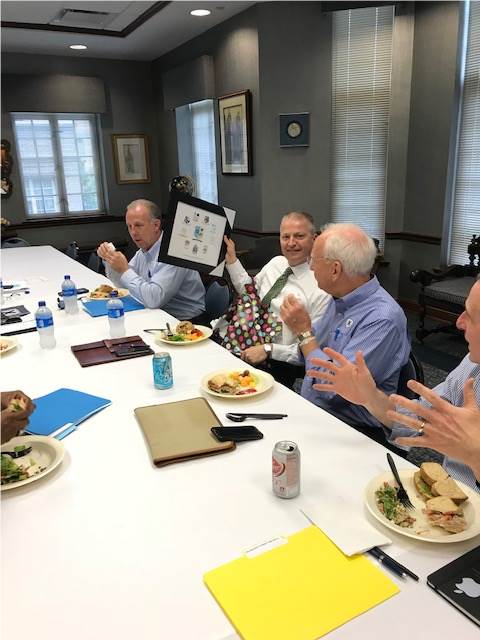 Photo of four men sitting at a table eating food and talking to each other