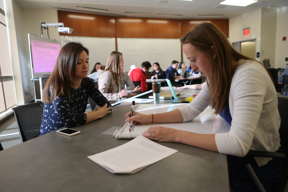 Two female students working together in a classroom.