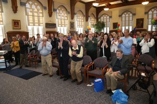 Photo of Fr. George Traub in a Conference Room with everyone else applauding