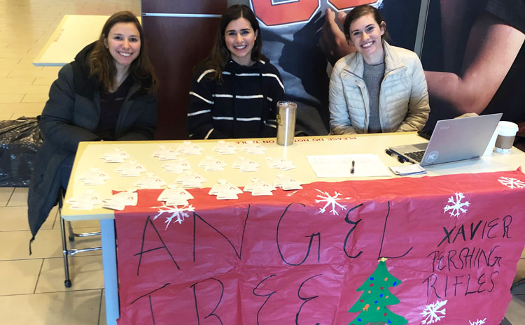 Three members of the Xavier Perishing Angels at their holiday booth outside the Caf.