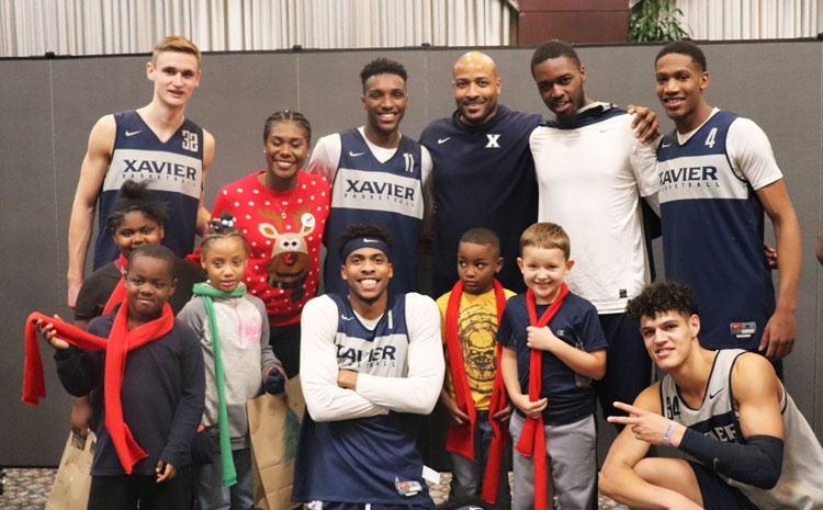 Xavier students smiling with kids during the annual A Xavier Christmas celebration.