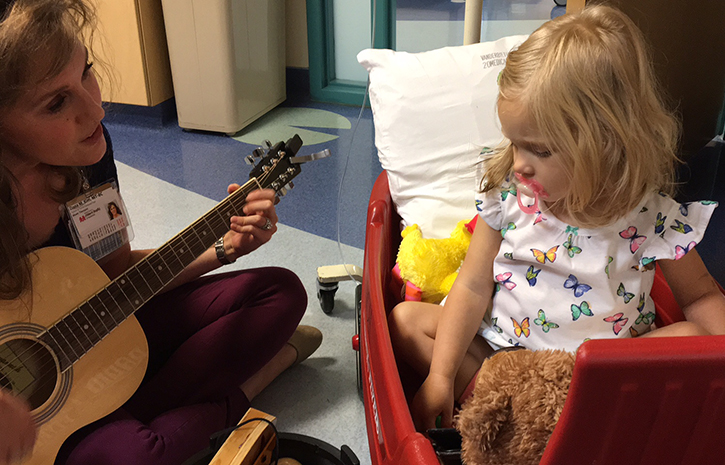 Picture of Dana Kim playing a guitar to comfort a Child