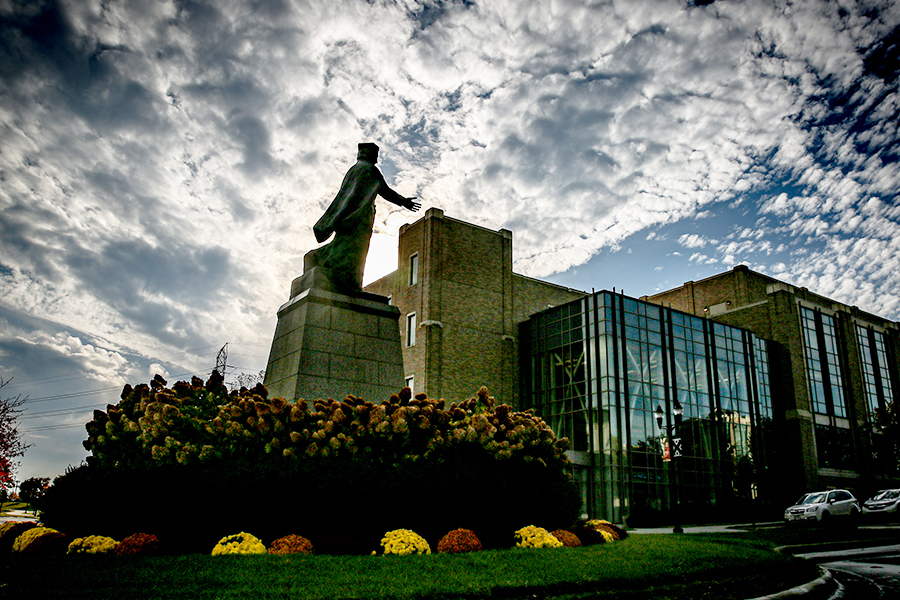 Photo of the St. Francis Xavier statue located on St. Francis Xavier Way on campus. Smith Hall is in the background.