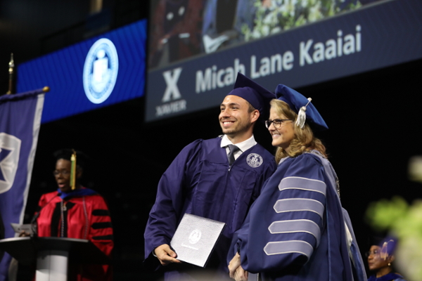 Graduate Micah Lane Kaaiai shakes Xavier President Colleen Hanycz's hand on stage in Cintas Center Arena.