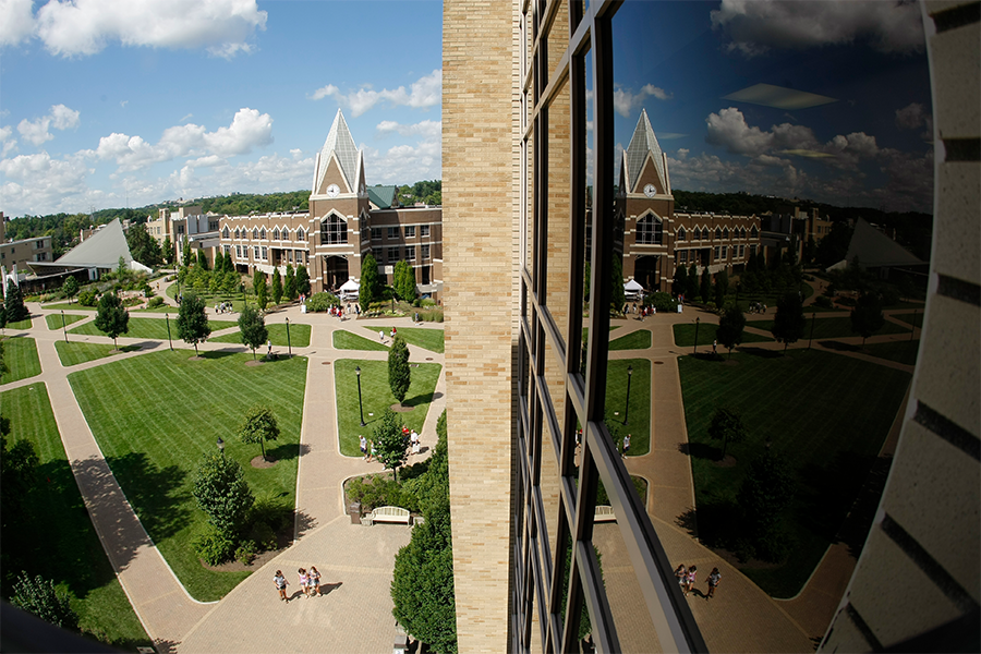 Xavier University's Gallagher Student Center and its clocktower are prominently displayed in the reflection from a building's windows.