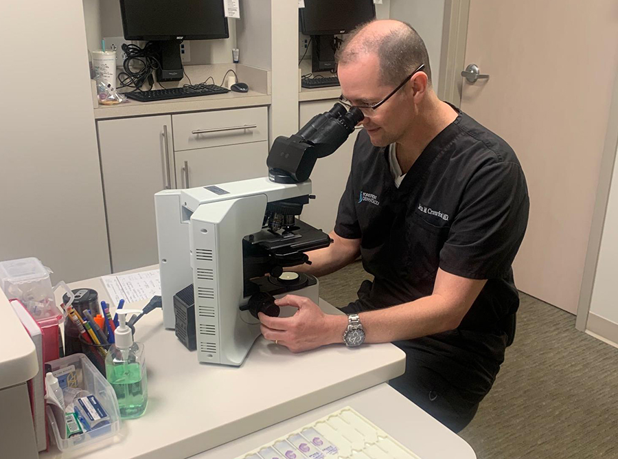 Xavier alum Kevin Crawford, M.D. ('98) looks through a microscope in a medical lab