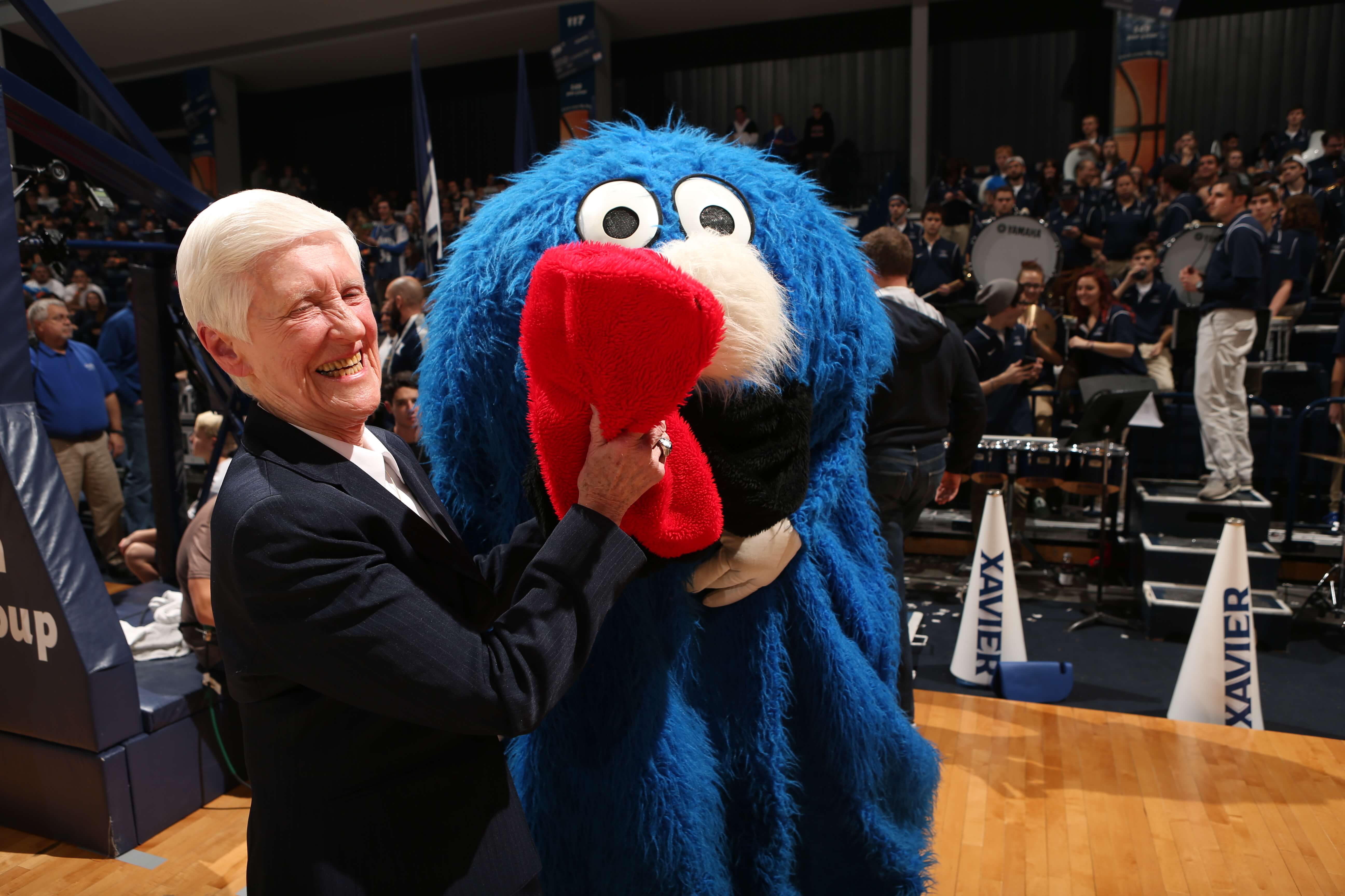 Sr. Rose Ann Fleming smiles with Xavier mascot, The Blob, at a Xavier basketball game