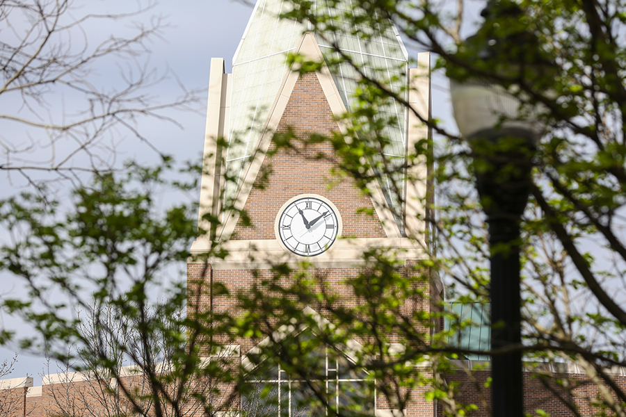 Xavier University's clocktower is seen through the leaves of some trees on campus.