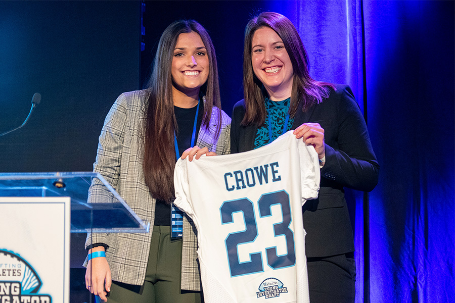 Xavier University biology professor Kelley Crowe holds up a football jersey with her name on the back at the Uplifting Athletes 2023 Young Investigator Draft.