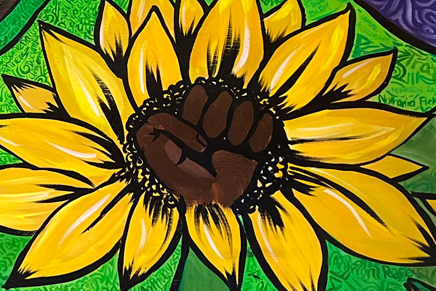A close-up of a bench shows a design of a Black fist in the form of a sunflower