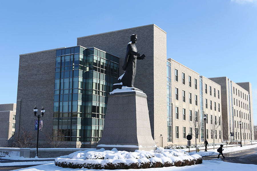 A statue of Saint Francis Xavier stands in front of Xavier University's Williams College of Business after a day of snowfall.
