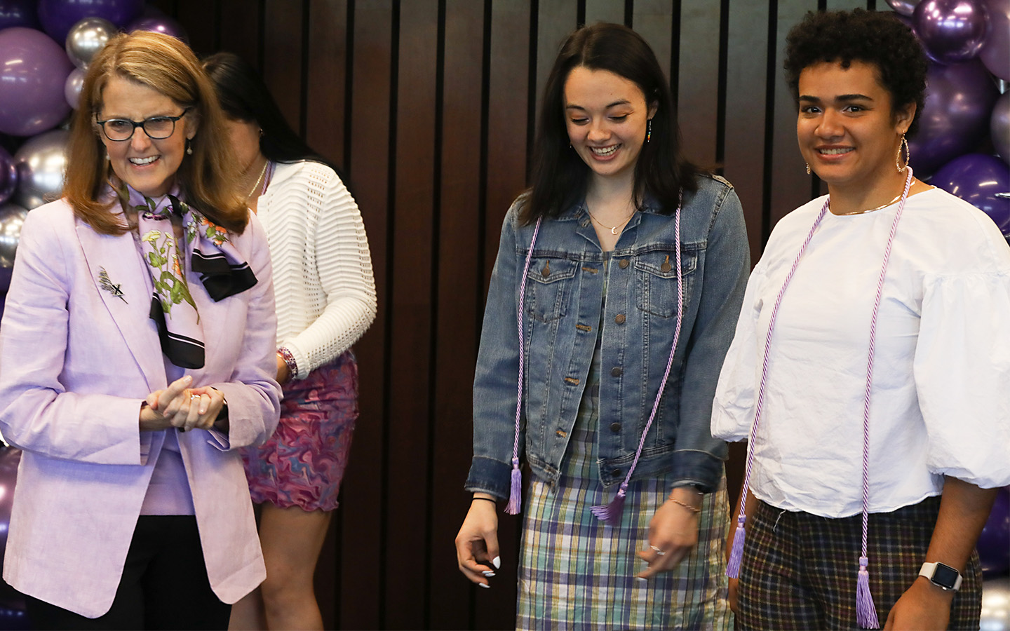 Sydney Bowie wears purple graduation cords and celebrates Lavender Graduation alongside Dr. Colleen Hanycz and another graduating senior