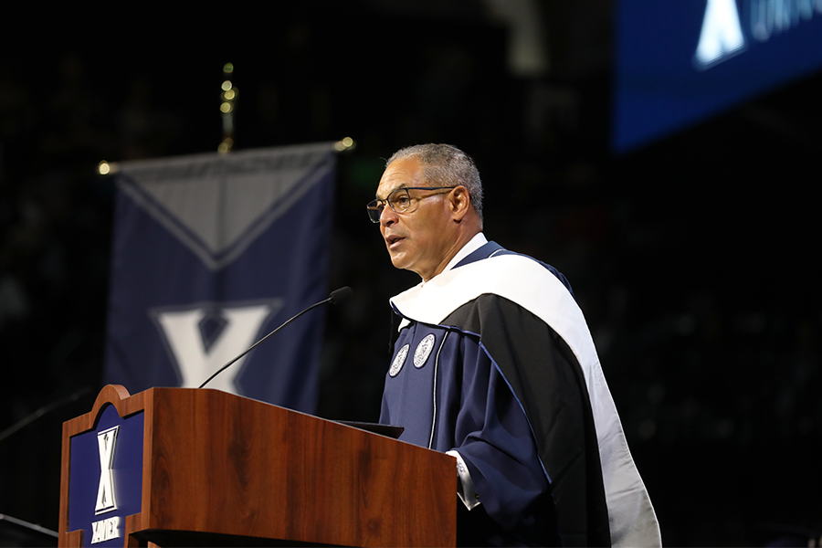 Retired four-star general Michael Garrett stands at a podium dressed in regalia at Cintas Center during Xavier University's 2023 Undergraduate Commencement Ceremony.