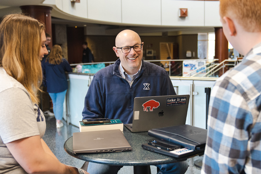 Mack Mariani smiles while talking with students at a table in GSC