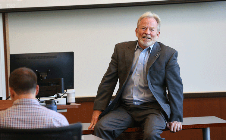 Tom Hayes, Dean of the Williams College of Business, talking with a group of students inside a classroom