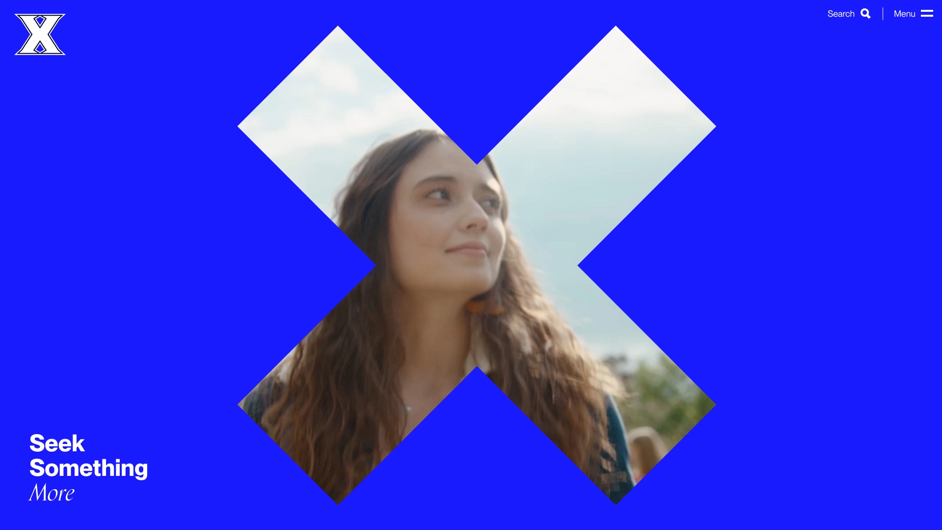 screenshot of the new xavier.edu homepage. Blue background with a x logo, which is filled in with the face of a student.