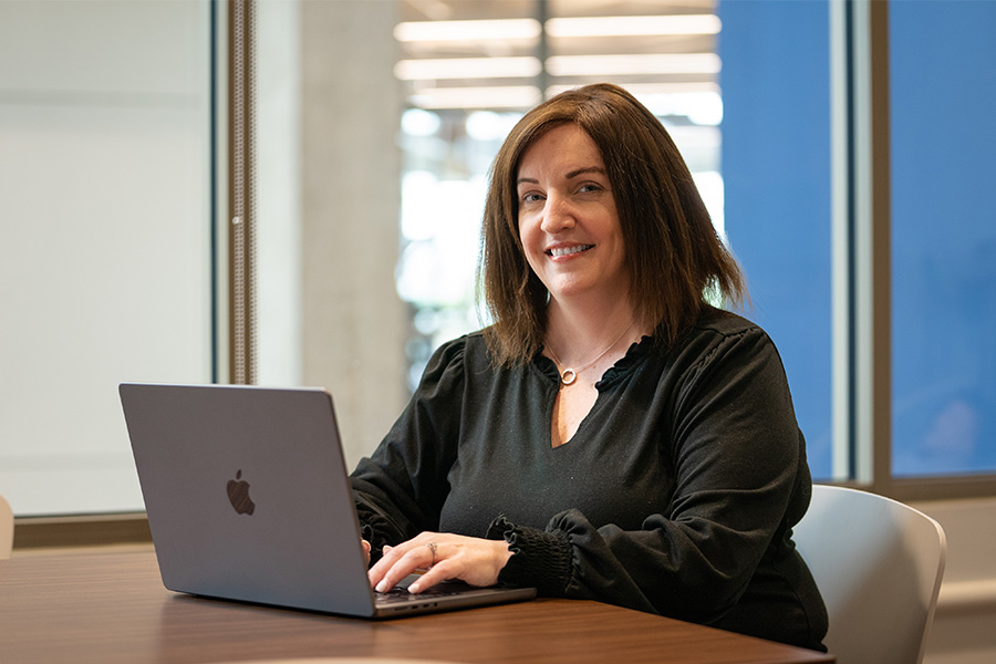Xavier nursing professor Terri Enslein sits at a desk with a laptop open in front of her
