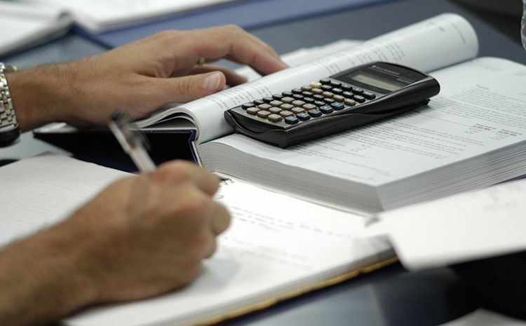 Photo of Someone using a Textbook and Calculator