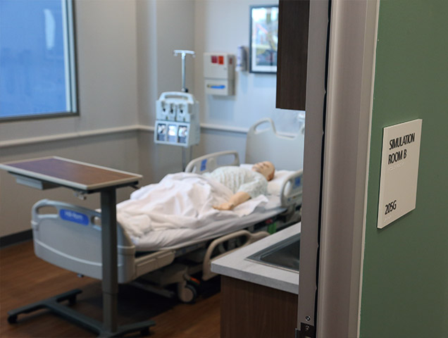 Nursing classroom at Xavier, with desks and hospital beds