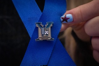 Student's hand on lapel after getting Xavier pin pinned in ceremony