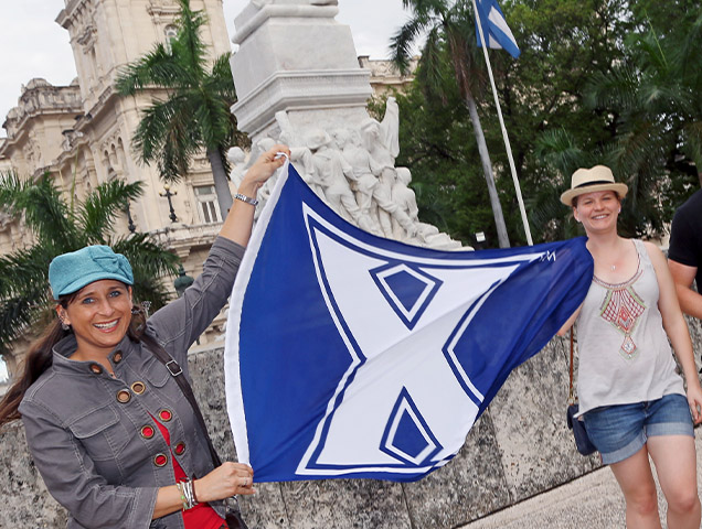 Students in the early childhood education major holding a Xavier flag on a trip abroad