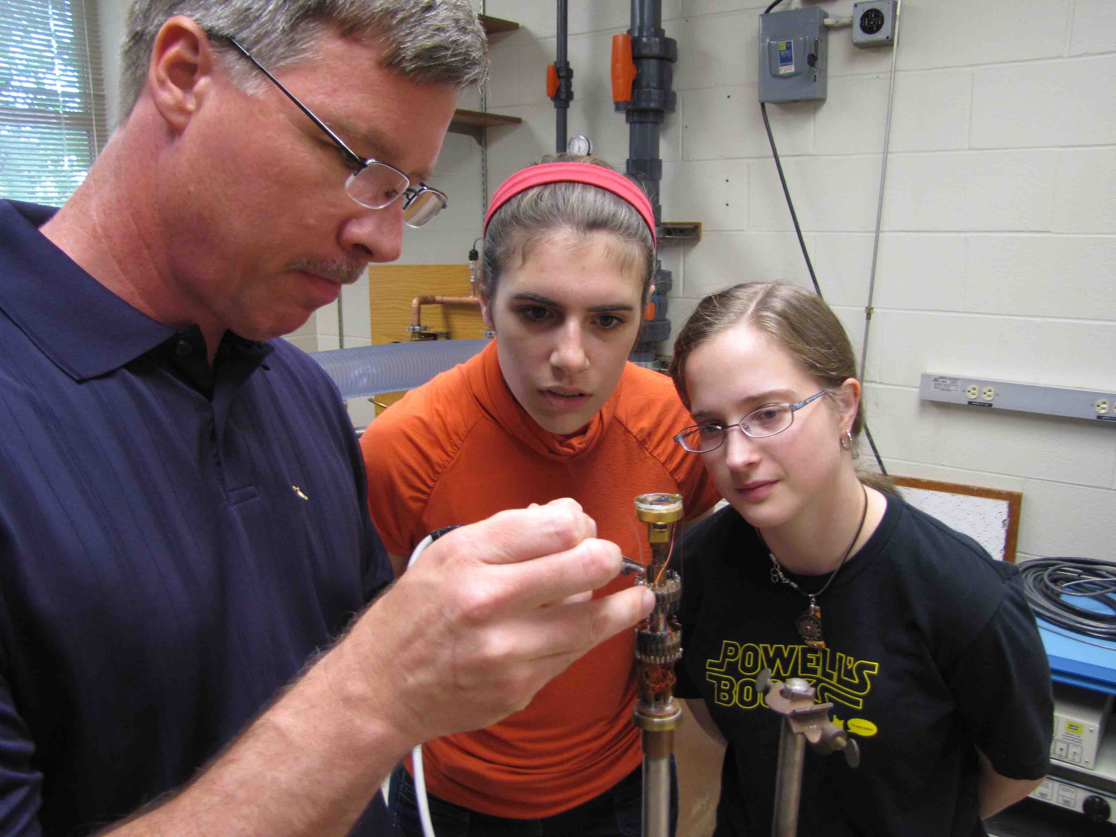 A professor showing students how to use a machine in a lab