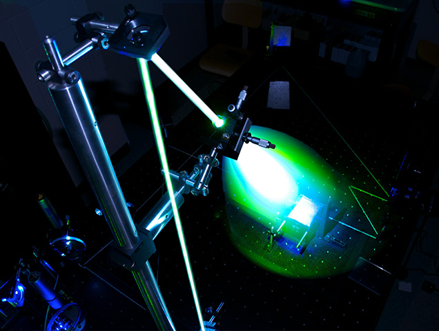 A large piece of lab equipment, used by students in the physics major, emitting a green laser light
